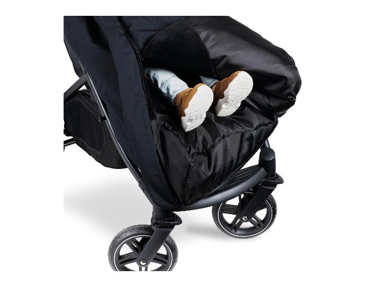 Kind im Kinderwagen-Fußsack, nur die Füße mit Schuhen ragen heraus.