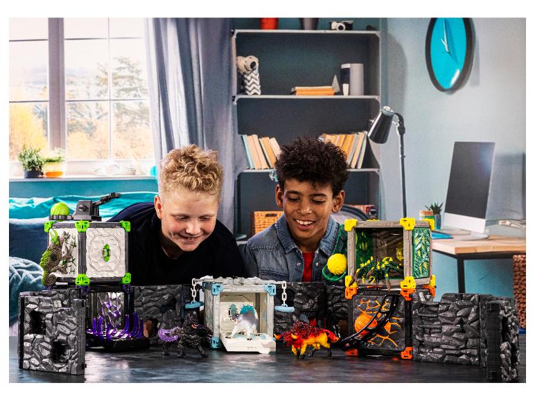 Zwei Jungen spielen mit einem Spielzeugset mit Monstern und Höhlen.