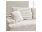 Cremefarbenes geripptes Cordsofa mit Kissen, in hellem Interieur.