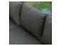Detail eines dunkelgrauen Stoffsofas mit Kissen, vor verschwommenem grünem Hintergrund.