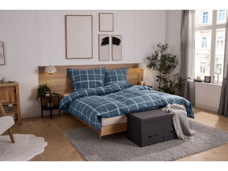 Schlafzimmer mit blauer karierter Bettwäsche, Holzkopfteil und Nachttischen.