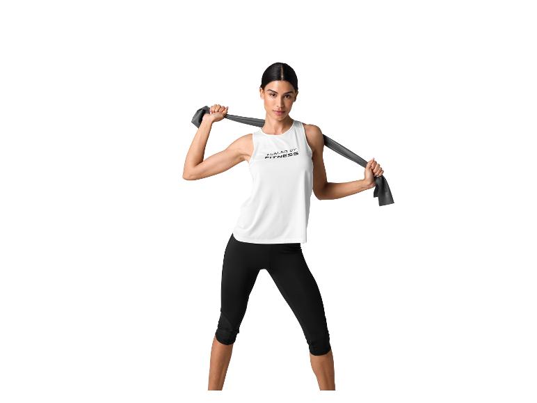 Frau in weißem Top und schwarzen Leggings, hält ein graues Widerstandsband.