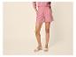 Frau in rosa Hemd und Shorts, mit beigen Sandalen.