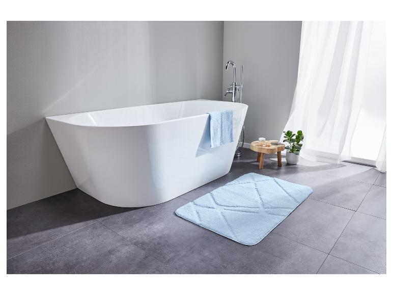 Eine weiße Badewanne mit einem blauen Badeteppich in einem modernen Badezimmer.