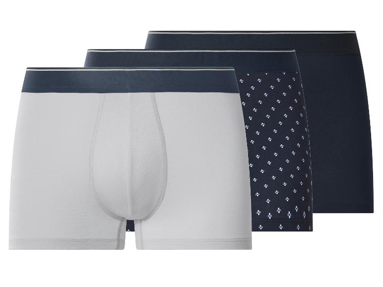 Drei Herren-Boxershorts: eine hellgraue, eine dunkelblaue mit Muster und eine einfarbige dunkelblaue.