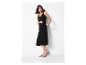 Eine Frau in einem schwarzen Kleid und beigen Sandalen.
