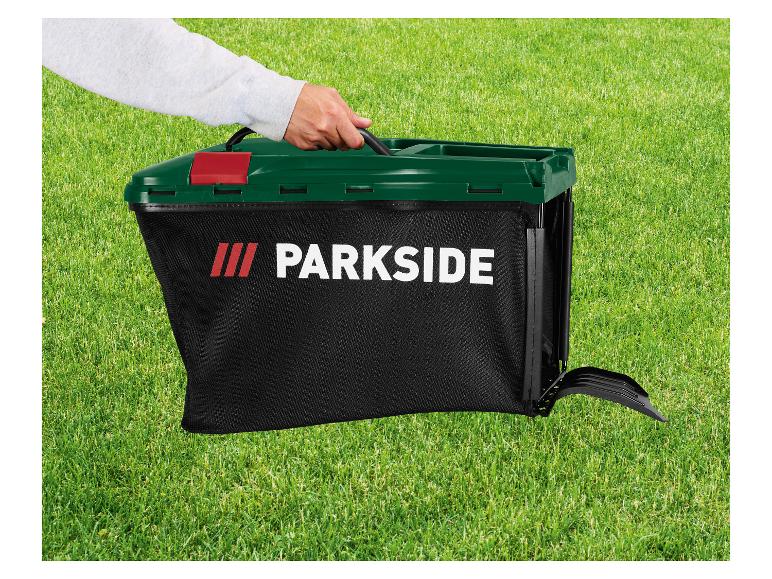 Hand hält einen schwarzen Parkside Grasfangkorb mit dunkelgrünem Deckel auf grünem Rasen.