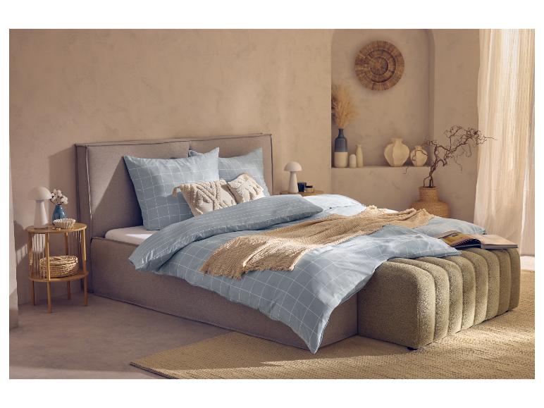 Schlafzimmer mit grauem Bett, hellblauer karierter Bettwäsche und Dekokissen.