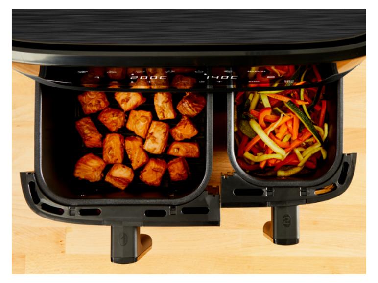 Doppelkorb-Heißluftfritteuse mit Lachsfiletstücken und Gemüse, die bei 200°C und 140°C garen.