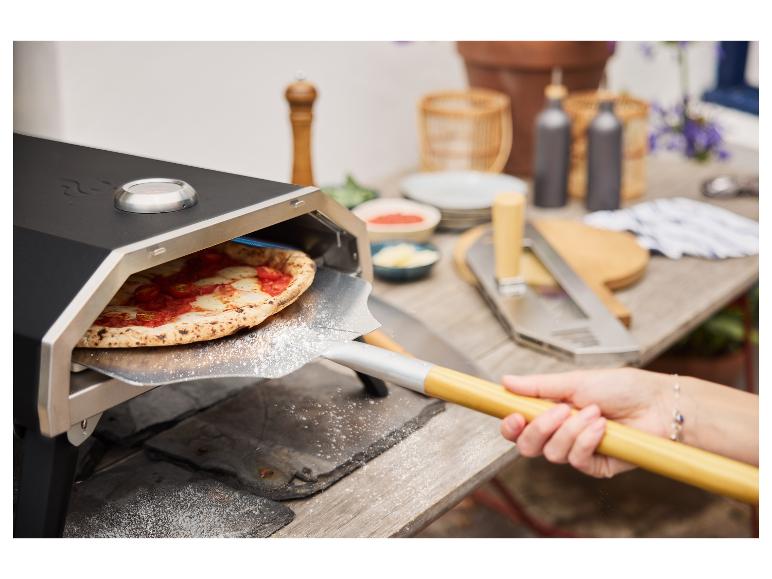 Pizza aus einem Pizzaofen mit Pizzaschieber entnehmen.