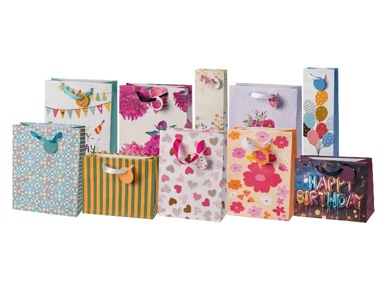 Sortiment bunter Geschenktüten mit verschiedenen Mustern wie Blumen, Herzen, Streifen und „Happy Birthday“-Text.