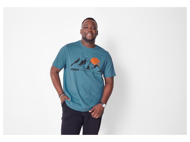 Ein Mann trägt ein türkisfarbenes Columbia-T-Shirt mit Bergmotiv.