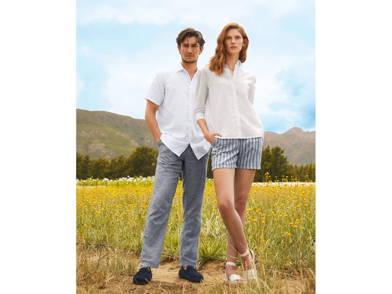 Mann und Frau in weißen Hemden und sommerlicher Kleidung auf einem Blumenfeld.