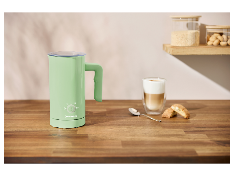 Ein grün-beiger Milchaufschäumer von SilverCrest auf einem Holztisch.