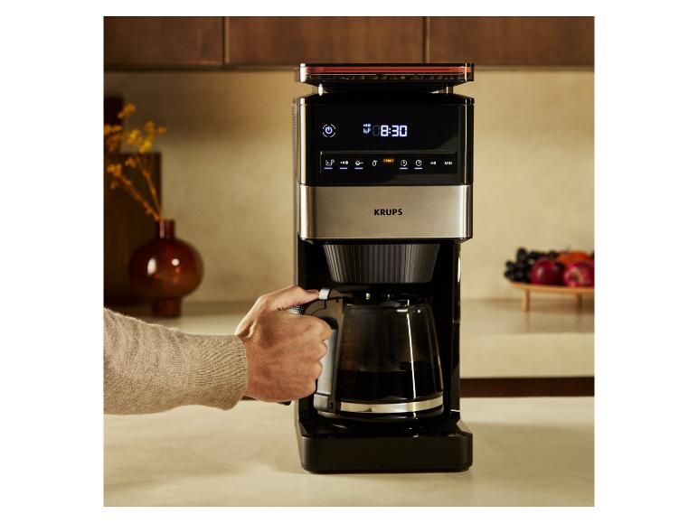 Kaffeemaschine mit Digitalanzeige und Kanne, von einer Person bedient.