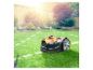 Mähroboter auf grünem Rasen mit Garten im Hintergrund