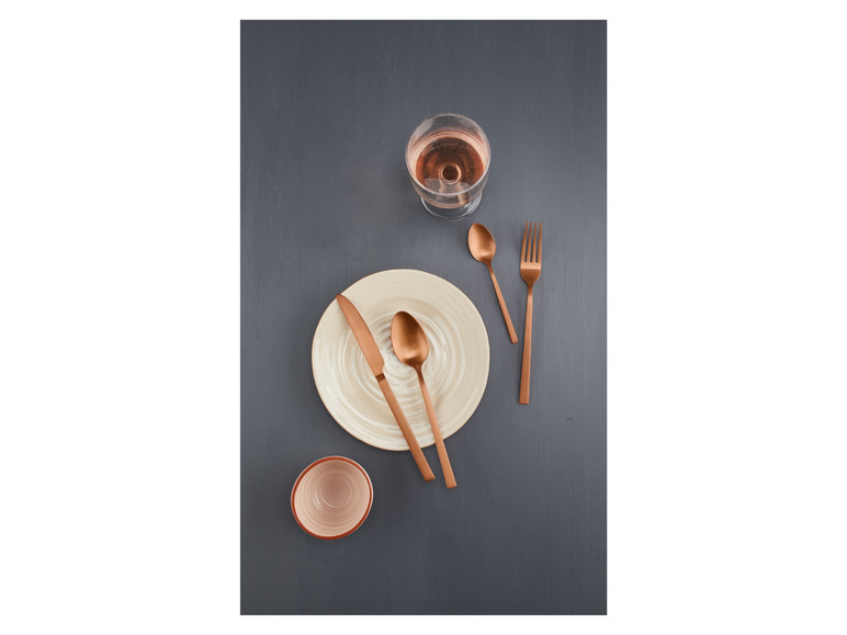 Ein Teller mit Besteck und einem Glas Roséwein.