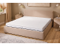 Beiges Bett mit Matratze und weißem Topper in einem Schlafzimmer mit Holzboden.