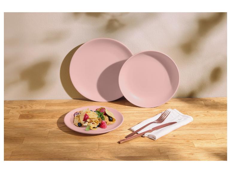 Pastellrosa Teller mit Fruchtcrepes und Kupferbesteck auf einem Holztisch.