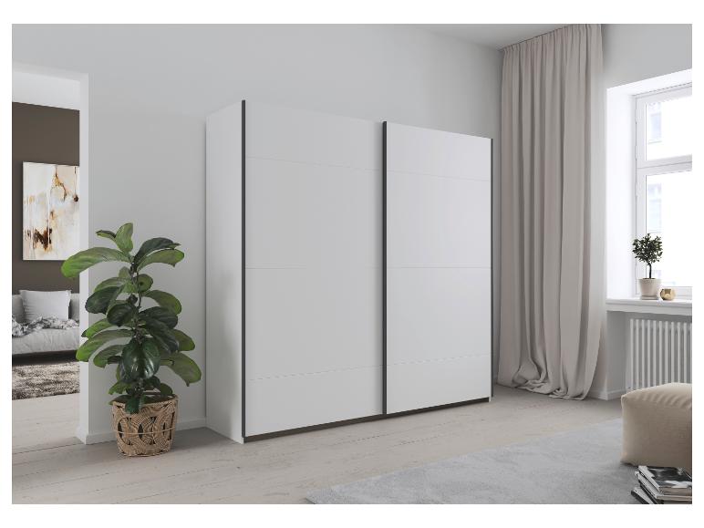 Weißer Schiebetürenschrank in einem modernen Schlafzimmer mit Pflanzen und Fenster.