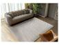 Modernes Wohnzimmer mit beigem Sofa, Wellenteppich und Ledersessel.