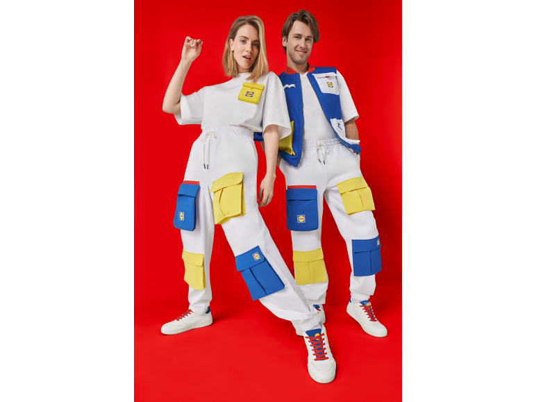 Zwei Personen in weißer Sportkleidung mit blauen und gelben Taschen, weißen Sneakern.