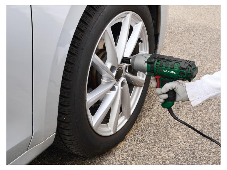 Person benutzt einen elektrischen Schlagschrauber zum Reifenwechsel am Auto.