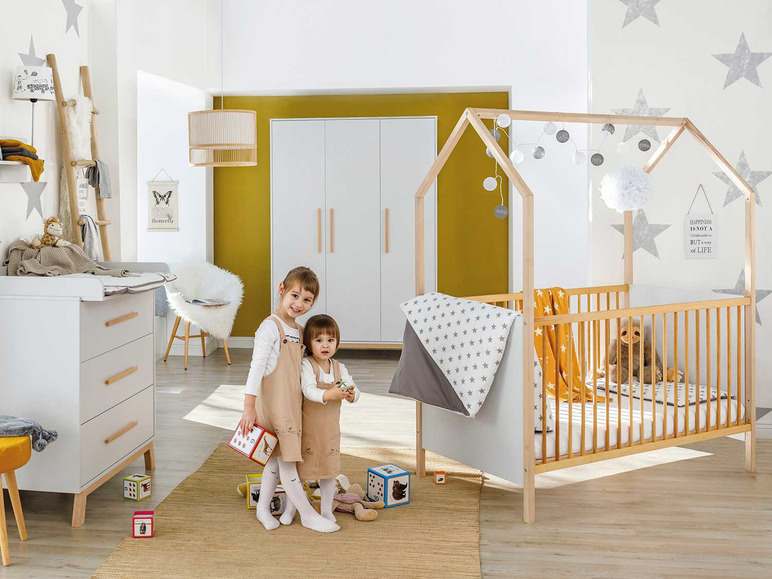 Ein Kinderzimmer mit einem Holzbett, einer Kommode und Spielzeug.