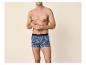 Mann oberkörperfrei in Boxershorts mit Palmen- und Ananas-Print.