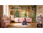 Mädchen liest in einem Wald-Kinderzimmer mit Holzbett, rosa Bettwäsche und Stauraum.
