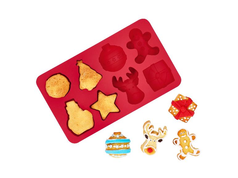 Rote Silikonform mit Weihnachtsplätzchen und dekorierten Keksen