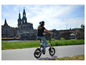 Eine Frau fährt ein graues Sachs E-Bike in der Nähe einer Brücke.
