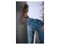 Mann in weißem T-Shirt und blauen Jeans, der ein Tattoo auf seiner Hand zeigt.