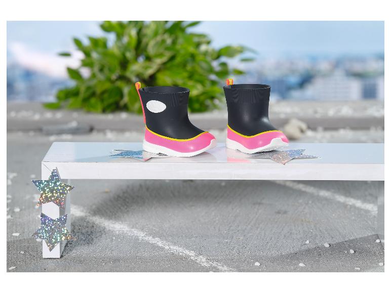 Schwarze und pinke Kindergummistiefel auf einer weißen Bank mit Sternendekorationen.