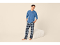 Lächelnder Mann in blauem Pyjama und karierter Hose, mit dem Motiv „Coffee is my therapy“.
