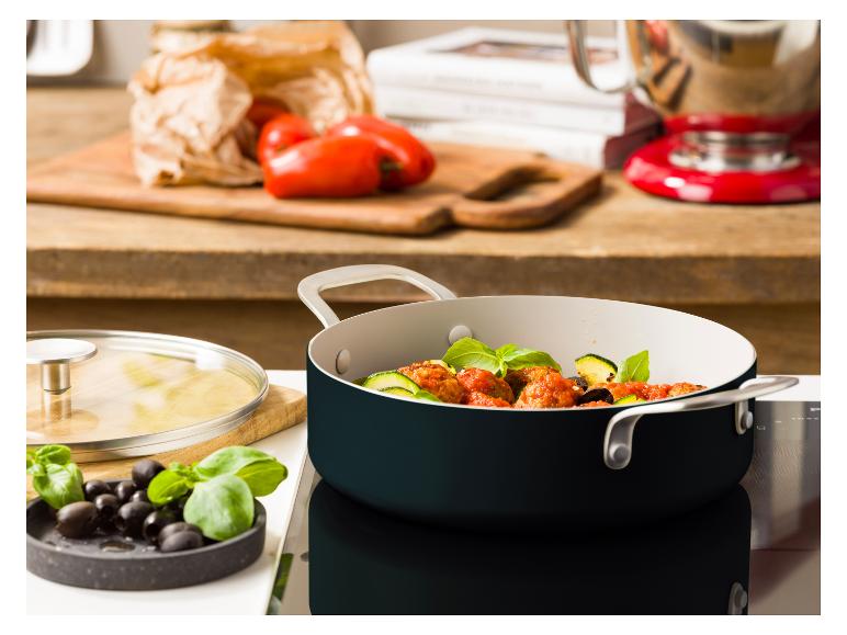 Topf mit Fleischbällchen und Gemüse auf einem Kochfeld in der Küche.