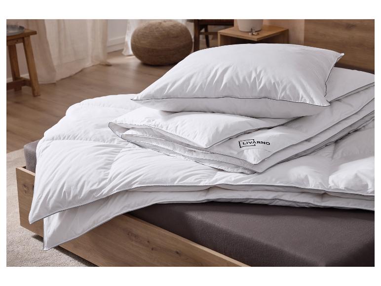 Weißes Kissen und Bettdecke mit grauen Rändern auf einem Holzbett.