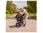 Frau befestigt eine Babyschale an einem Kinderwagen im Freien.