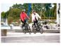 Zwei lächelnde Personen auf E-Bikes an einem Hafenpier.