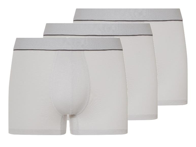 Drei weiße Boxershorts mit grauem Gummibund.