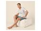 Lächelnder Mann in weißem T-Shirt und blauen Shorts sitzt auf einem Pouf.