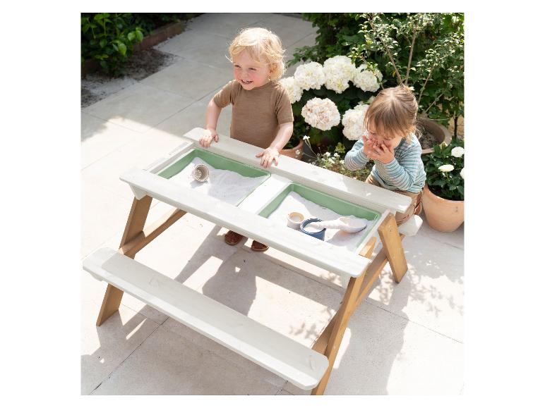Zwei Kleinkinder spielen draußen an einem Sand- und Wassertisch aus Holz.