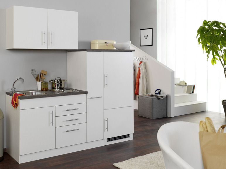 Weiße Küche mit Spüle, Kochfeld und Schränken.
