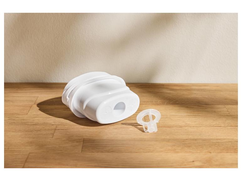 Ein weißer Wasserfilter und ein kleines transparentes Bauteil auf einer Holzoberfläche.