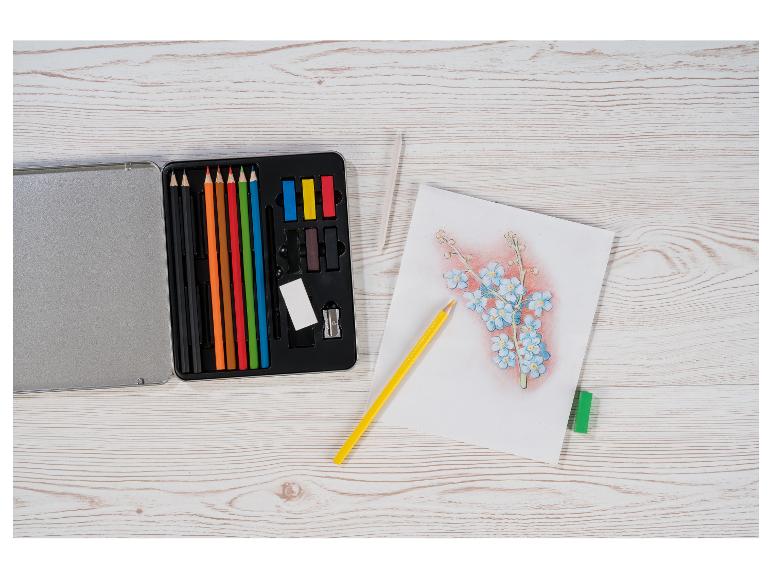 Kunstset mit Buntstiften, Pastellkreiden und einer Blumenskizze auf einem Holztisch.