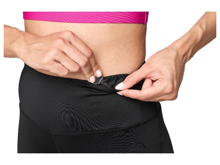 Frau steckt einen Schlüssel in die Tasche einer schwarzen Sportleggings.