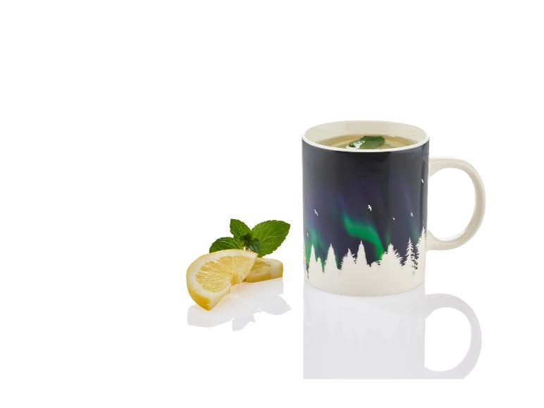 Eine Tasse mit einem Bild von der Aurora Borealis und einem Wald, mit einer Zitronenscheibe und Minze.