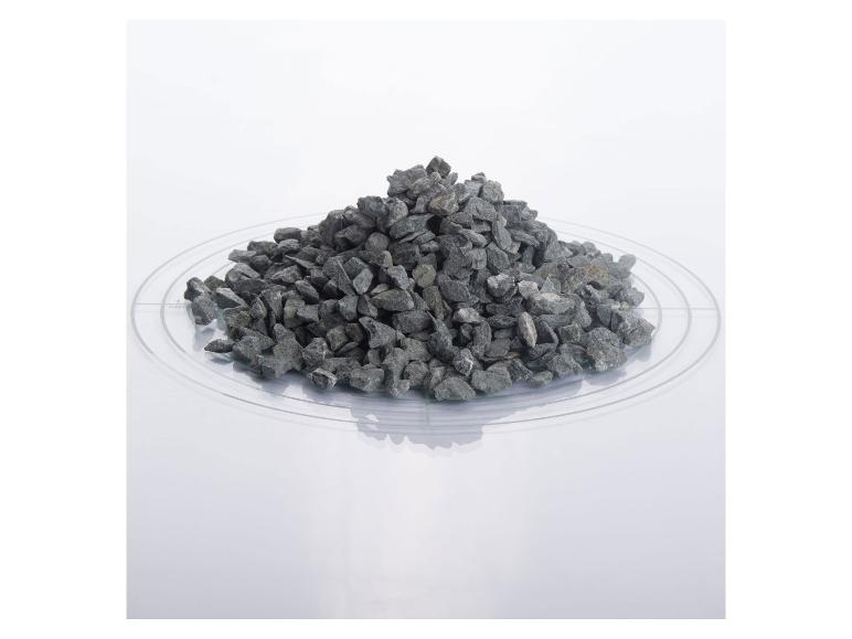 Ein Haufen grauer Steine auf einer transparenten Platte mit Messmarkierungen.