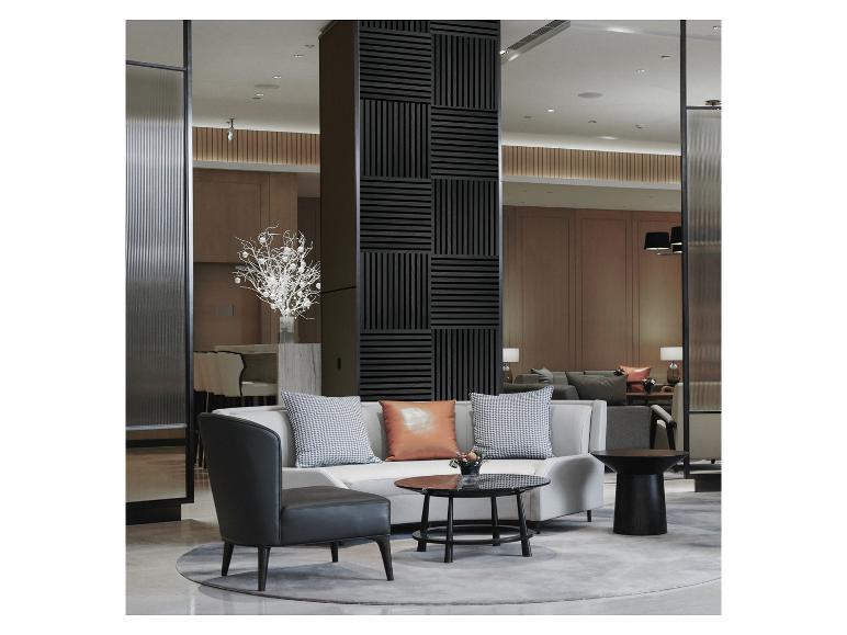 Graues Sofa mit Kissen, schwarzer Sessel und runde Couchtische in einem modernen Wohnzimmer.