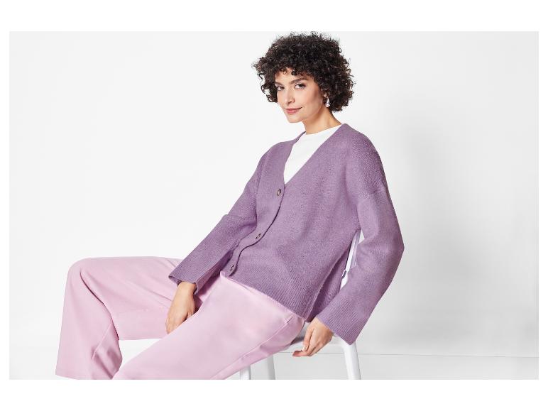 Model mit einem lila Strickcardigan und rosafarbenen Stoffhosen.
